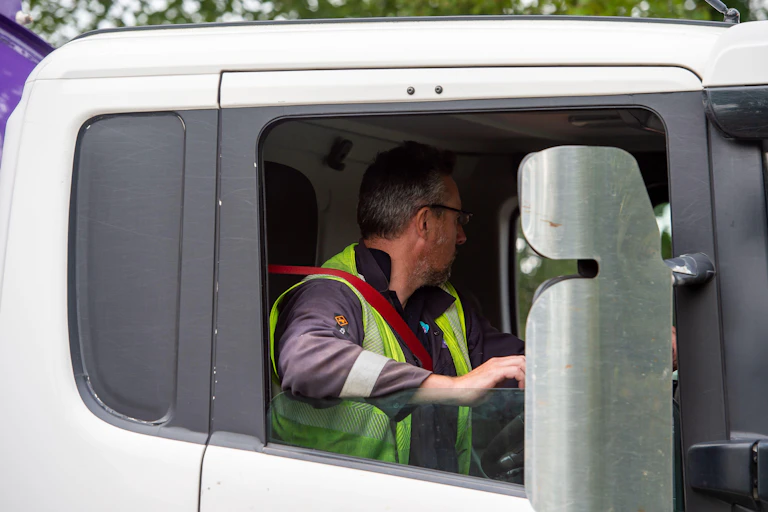 An HGV driver operating a lorry and looking away from the camera