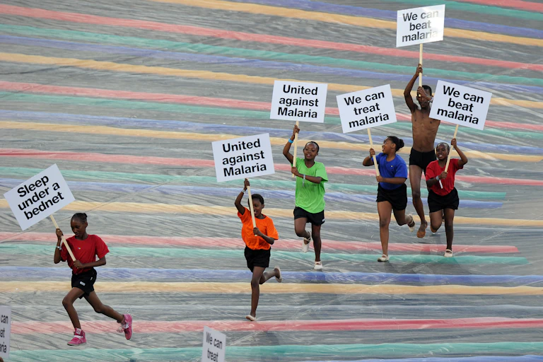 Children run with advertising banners for the fight against malaria during a ceremony held ahead of the 2013 African Cup of Nations final football match Nigeria vs Burkina Faso, on February 10, 2013 in Johannesburg.