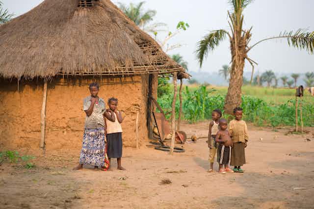 Une femme et des enfants devant leur maison en terre battue