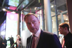 A man in a suit and tie leaves a TV studio at night.