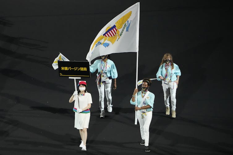 Four people march carrying a flag.