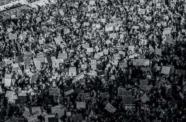 A black and white aerial image of a large protest.Some signs say: 'I can't breath,' others say, "Black Lives Matter," others: "No Justice no peace."