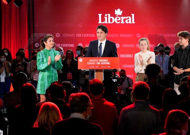 Justin Trudeau speaking at a podium with his wife Sophie Gregoire-Trudeau on one side and his children on the other.