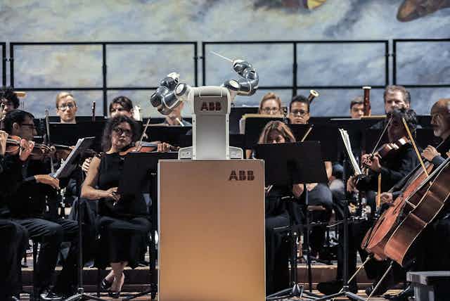 A robot conductor 'performs' in front of an orchestra.