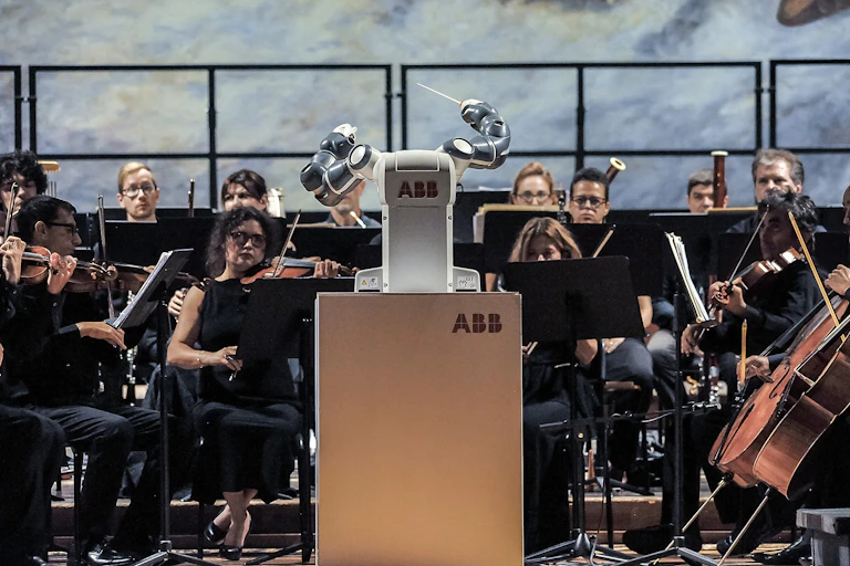A robot conductor 'performs' in front of an orchestra.