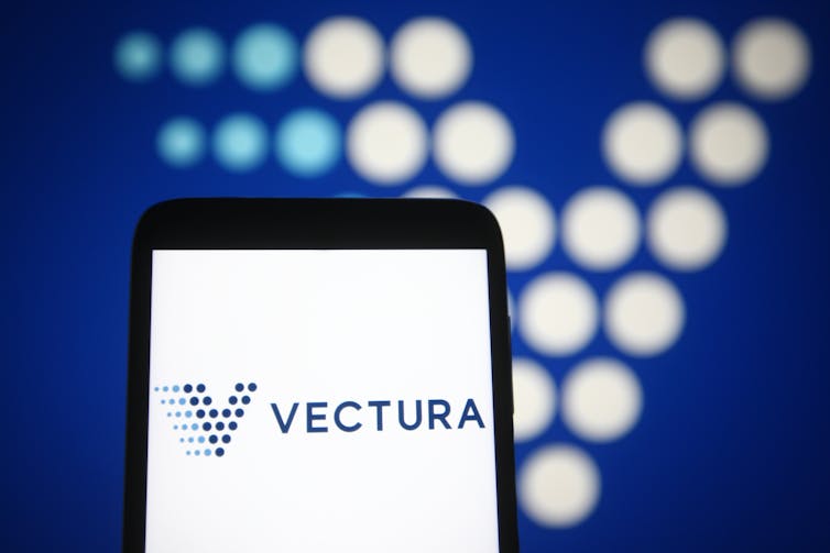 Blue-spotted 'V' Vectura logo on a smartphone and in the background.