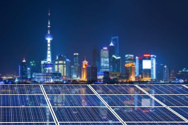 Shanghai skyline at night with solar panels in foreground.