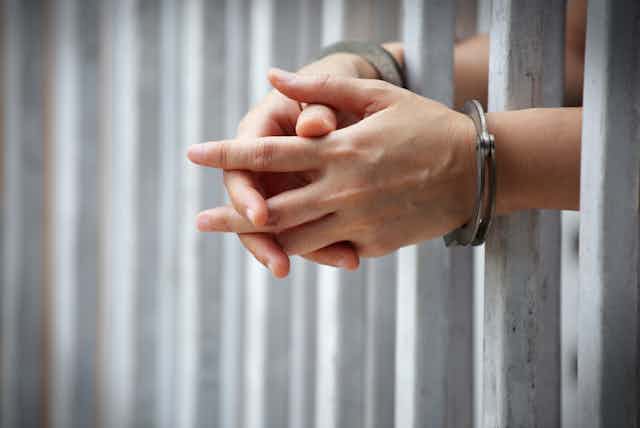 Close-up image of handcuffed hands in a jail cell