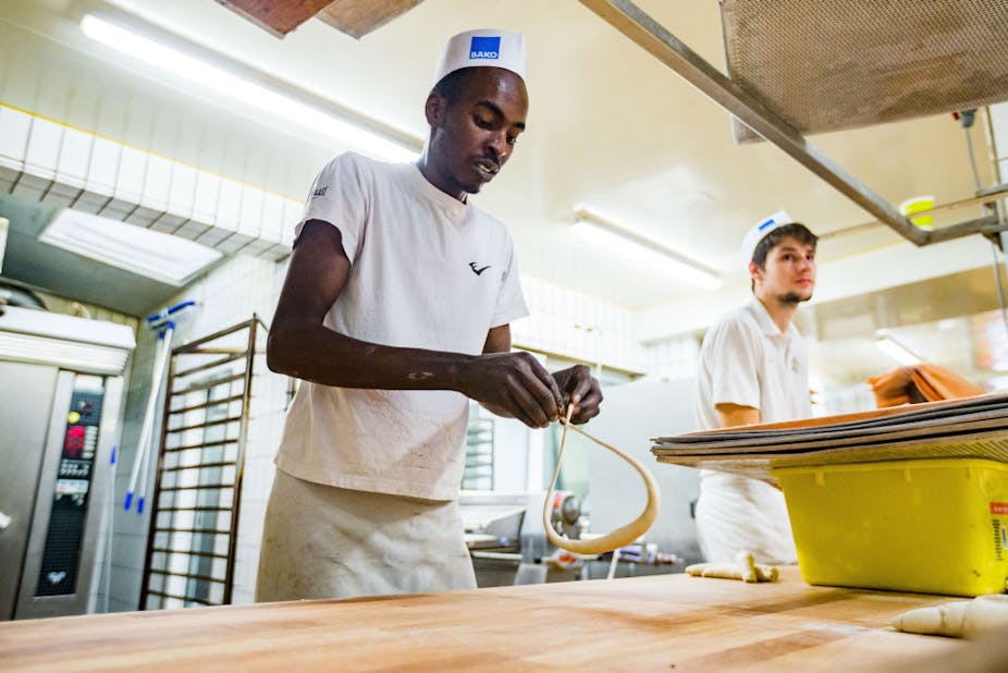 Anwar Albrnaoy, a refugee from Nigeria, works at the Baeckerei Berger bakery in Germany due to a government initiative. 