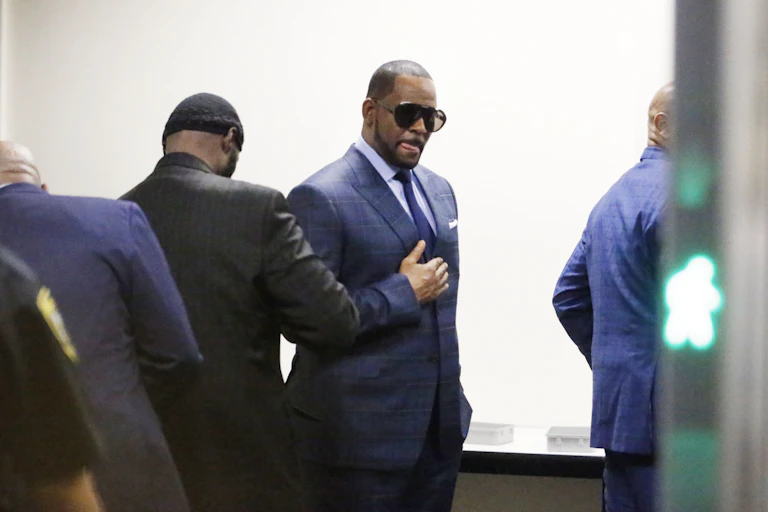 R. Kelly dressed in a suit and sunglasses walks through security checkpoint on the way to court.