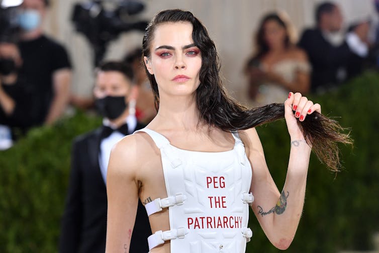 La mannequin anglaise Cara Delevingne arrive au Met Gala 2021, le 13 septembre 2021 à New York. Sur son gilet est inscrit « Peg the patriarchy » (« À bas le patriarcat »)