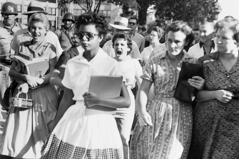 A Black girl walks away as white girls yell and glare at her