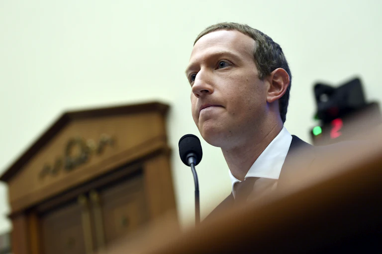 Mark Zuckerberg looks forward with a microphone by his mouth during testimony on Capitol Hill
