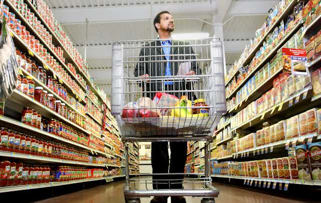 Man shops for groceries, pushing a cart