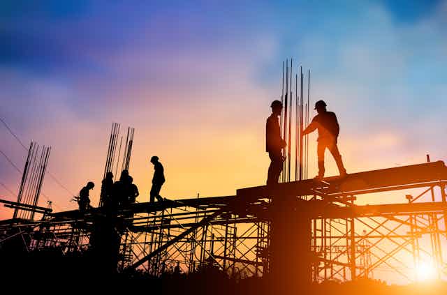 Workers stand on top of a construction site.