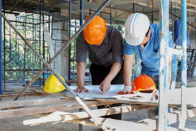 People look at building plans on a work site.