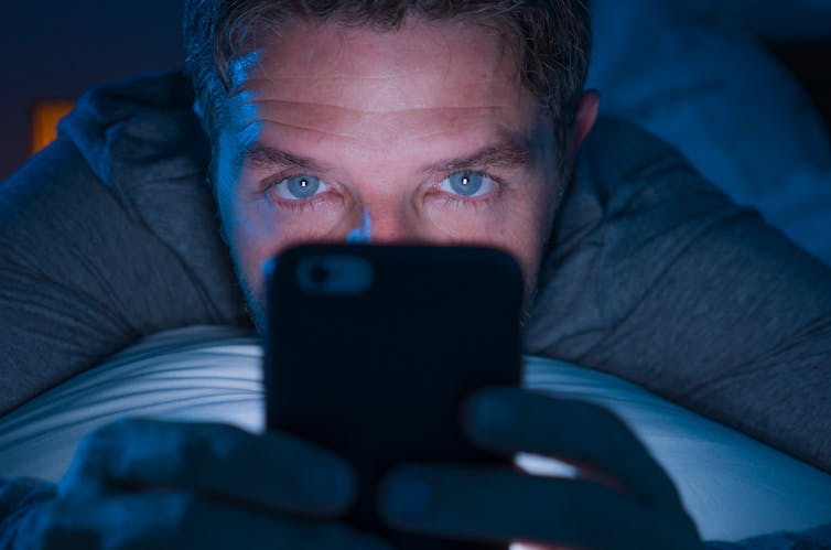 A man looks at his phone at night.