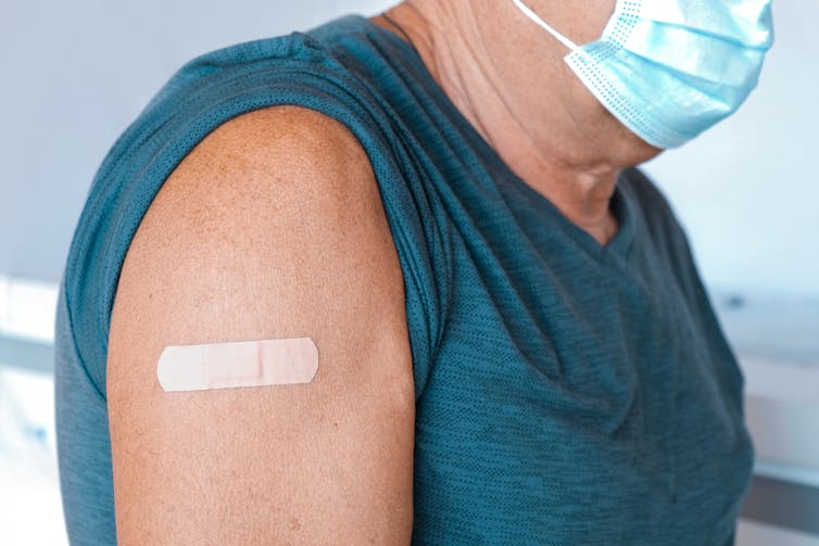 Older person's arm with a bandaid after being vaccinated.