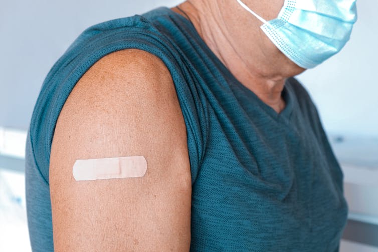 The arm of an elderly person with a bandage after being vaccinated.