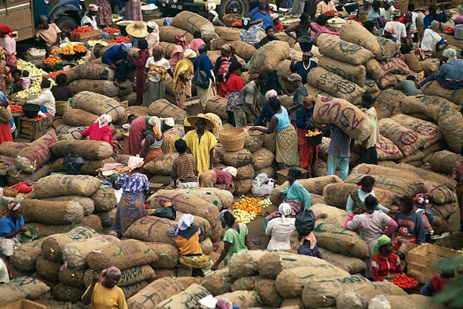 Men and women are pictured among piles of bags, with small food stalls dotted around them.