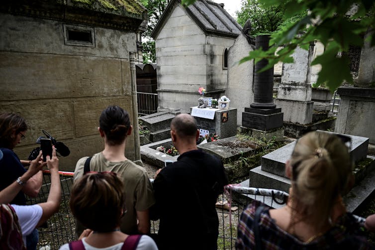Des personnes se recueillent sur la tombe du chanteur des Doors, Jim Morrison, pour commémorer le 50ᵉ anniversaire de sa mort au cimetière du Père-Lachaise à Paris, le 3 juillet 2021