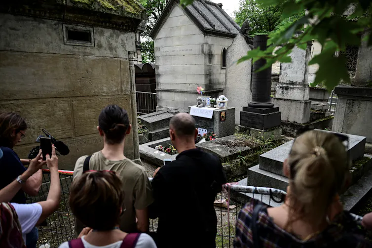 Des personnes se recueillent sur la tombe du chanteur des Doors, Jim Morrison, pour commémorer le 50ᵉ anniversaire de sa mort au cimetière du Père-Lachaise à Paris, le 3 juillet 2021