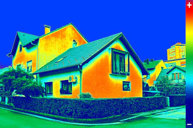 A detached house in infrared with orange walls depicting heat loss.