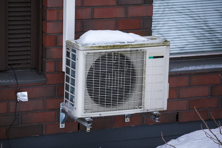 A square unit resembling an air conditioner mounted on an external brick wall.