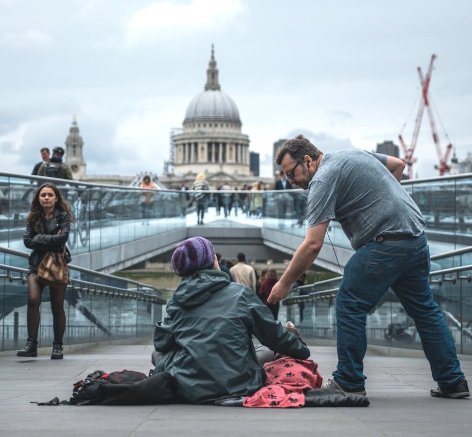 Man helping beggar woman with St Pauls in the background