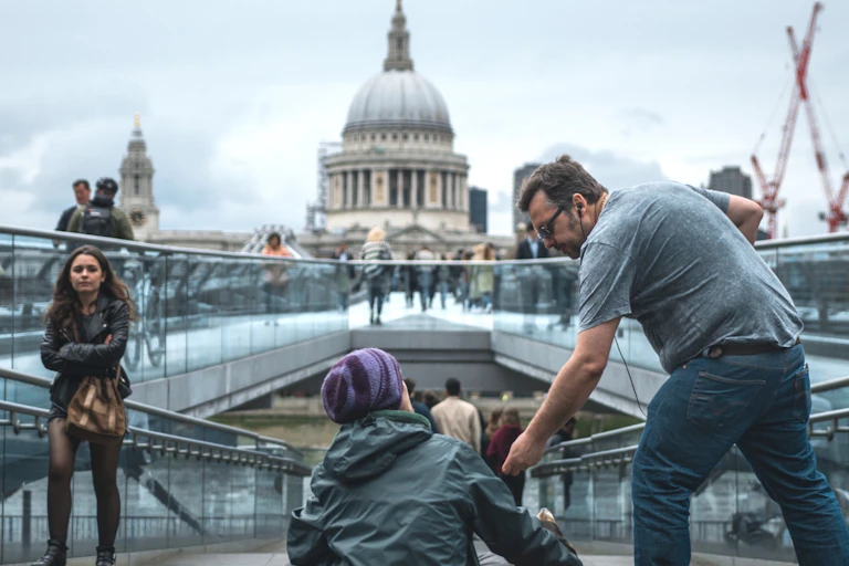Man helping beggar woman with St Pauls in the background