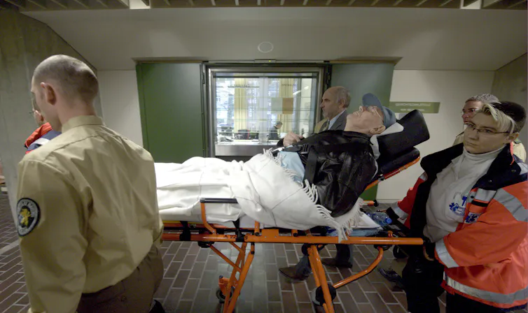 John Demjanjuk, an elderly man on a stretcher, is brought into court with the help of policemen and paramedics.