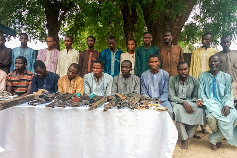 Men sitting with guns before them.
