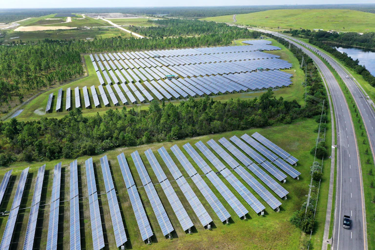 Fields of solar panels bounded by trees and a highway