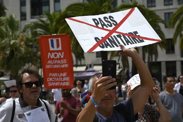 Un groupe d’anti-vax brandit des pancartes, « Non au passe sanitaire », « Non au pass sécuritaire et à la dictature sanitaire »