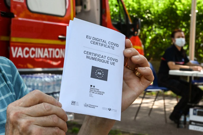 Un homme tient son passe sanitaire devant un site de vaccination contre la Covid.
