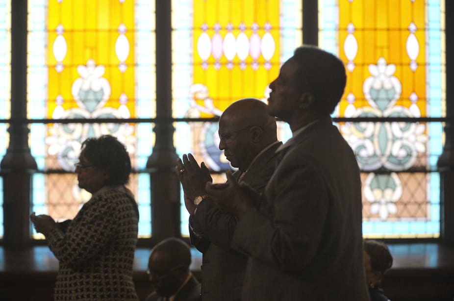 People standing in front of stained glass windows worship at John Wesley AME Zion Church in Washington, D.C.
