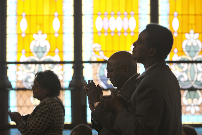 People standing in front of stained glass windows worship at John Wesley AME Zion Church in Washington, D.C.