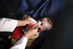 A baby is fed a supplement.