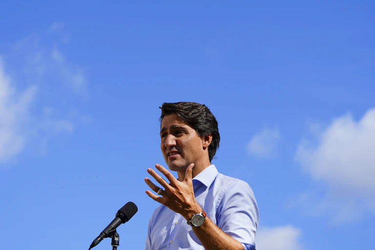 Justin Trudeau standing at a microphone with blue skies behind him