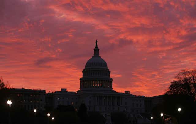 The early morning sun lights up the sky behind the U.S. Capitol.