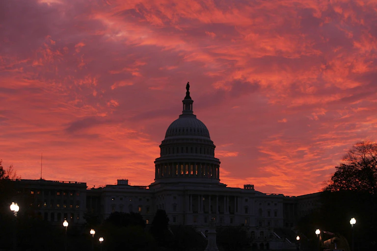 The early morning sun lights up the sky behind the U.S. Capitol.