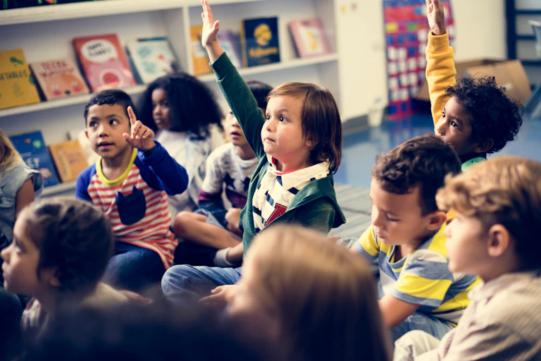 De jeunes enfants dans une classe, certains levant la main