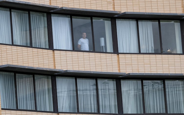 Man at window in quarantine hotel.