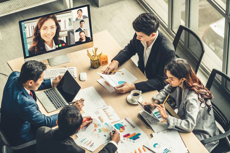 Business meeting combining participants seated at a table and in an online video call