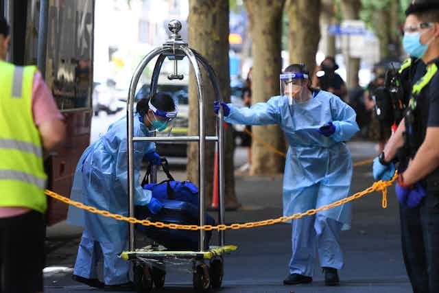 Hotel quarantine workers move luggage.