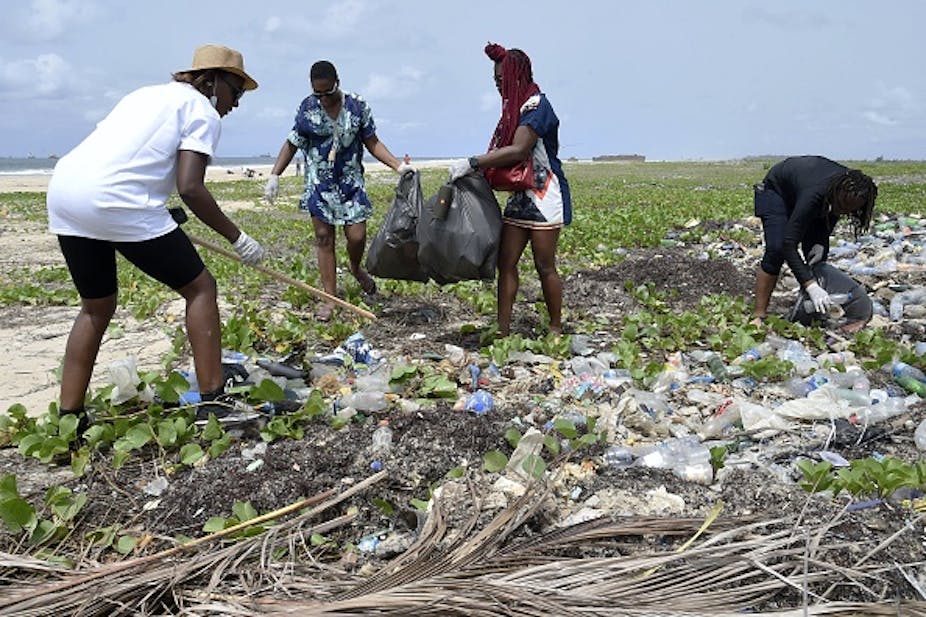 Four women gathering plastic waste and bagging them to dispose off properly.