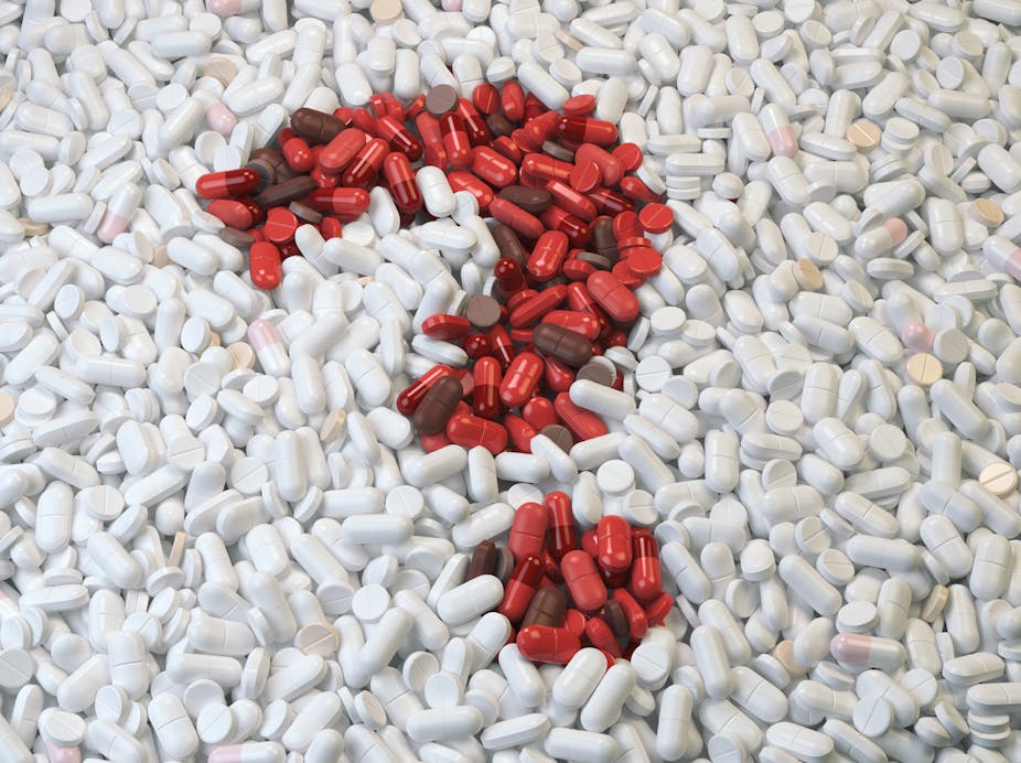 Un point d'interrogation fait de pilules rouges sur fond de pilules blanches.