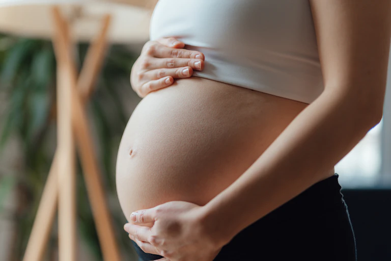 Midsection of a pregnant woman holding her belly