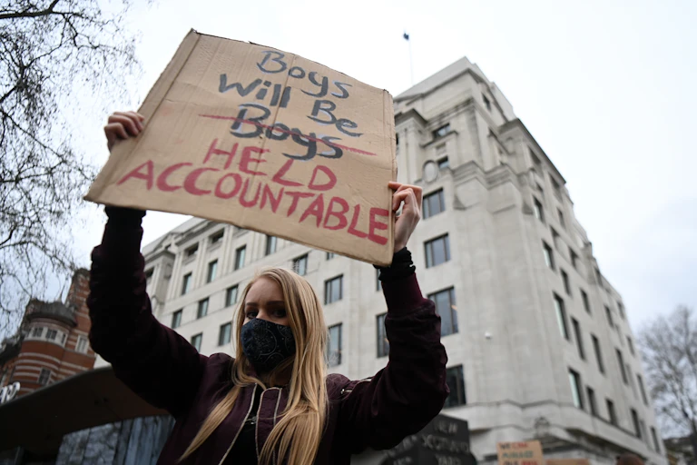 A protestor holds up a sign reading 'Boys will be held accountable'