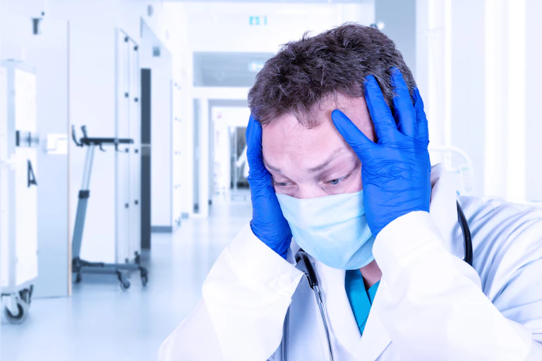 A distraught doctor, wearing mask and gloves, in despair after making a mistake during surgery.